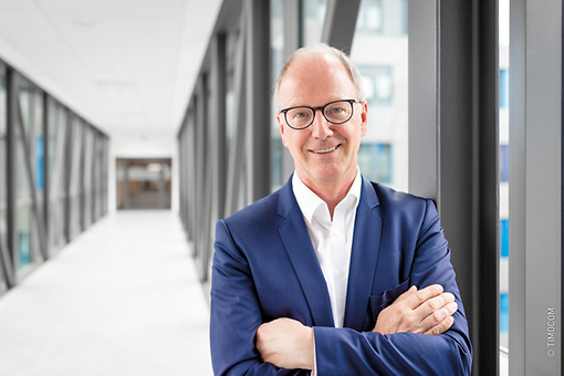 Gunnar Gburek im modernen TIMOCOM Gebäude, freundlich lächelnd mit verschränkten Armen. Gunnar Gburek im modernen TIMOCOM Gebäude, freundlich lächelnd mit verschränkten Armen.
